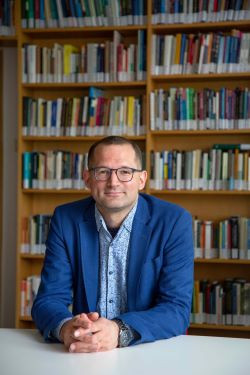 Prof. Dr. Höhne an einem Tisch sitzend. Im Hintergrund sieht man ein Bücherregal